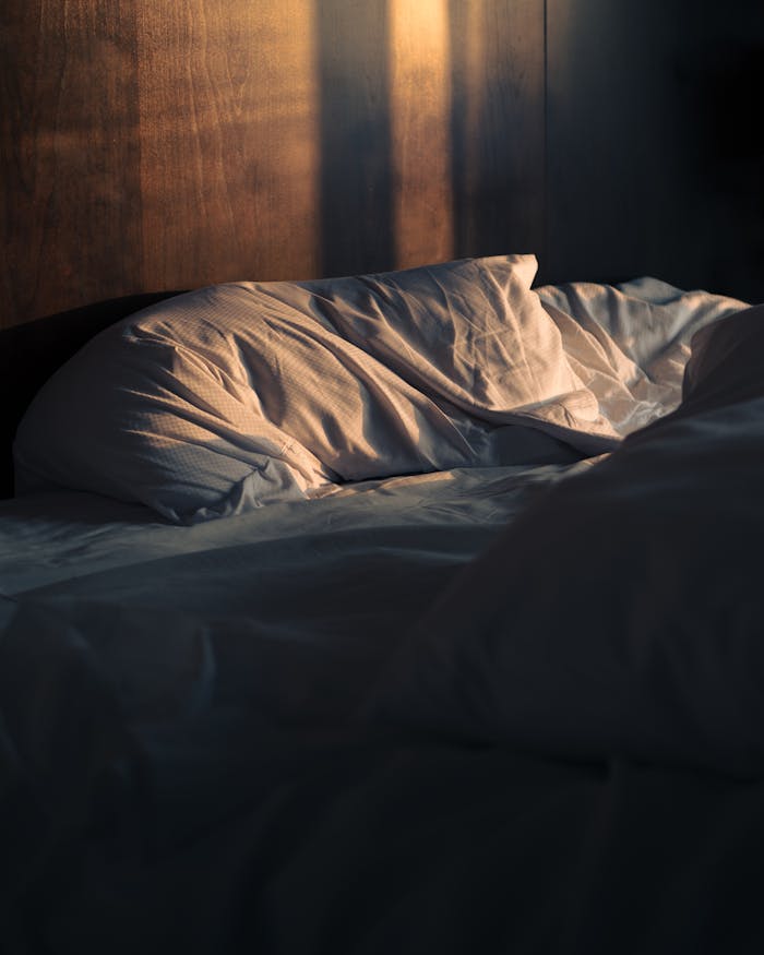 Relaxed bedroom scene with sunlight on cozy unmade bed in Ottawa, Canada.